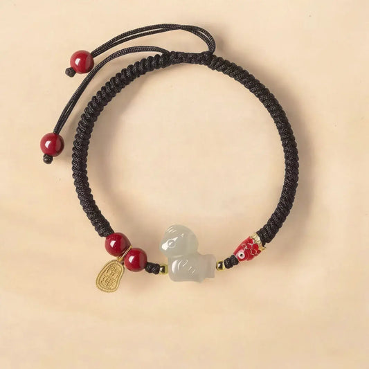 Black cord bracelet with red beads and a jade charm on a beige background