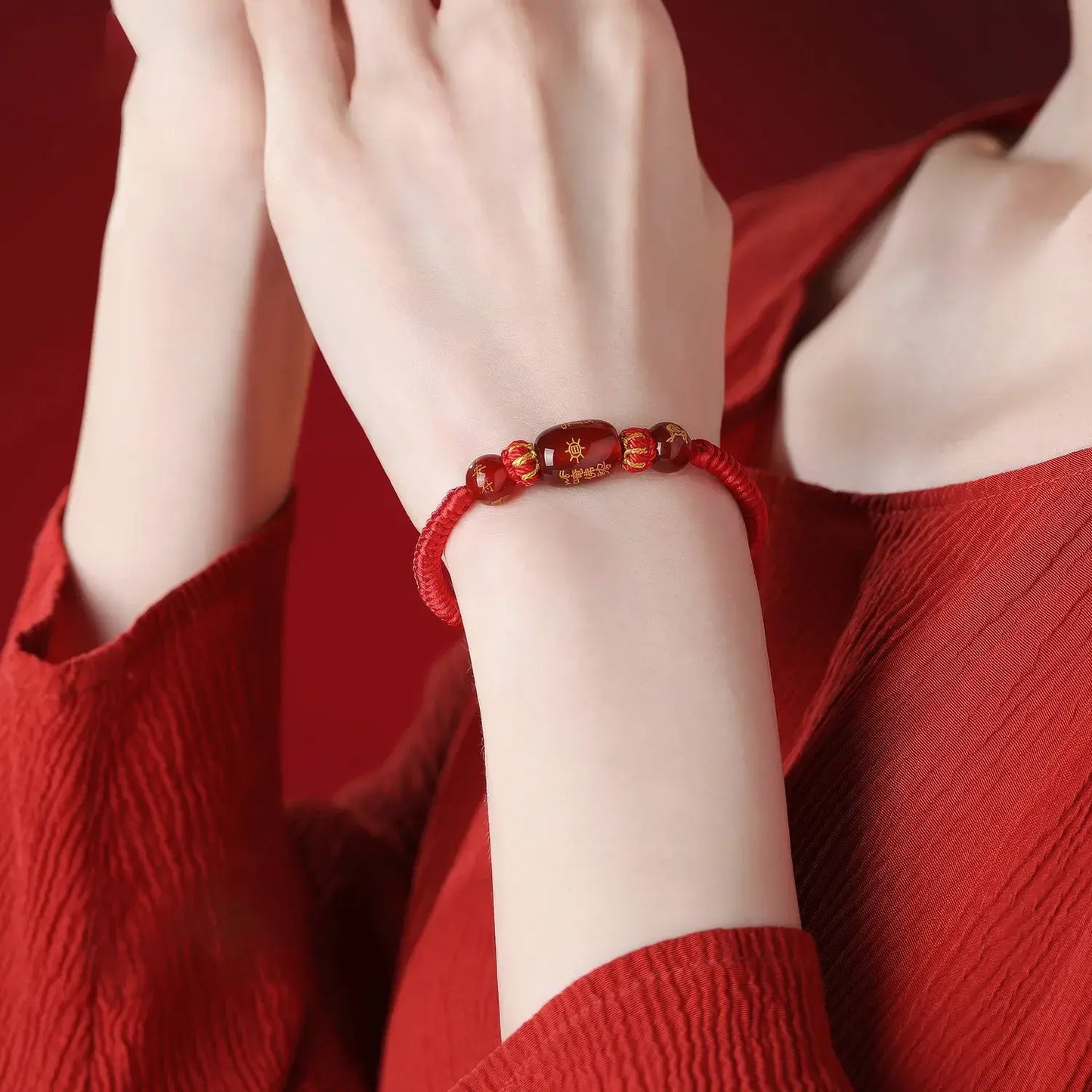 Person wearing a red beaded bracelet on a red background