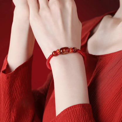 Person wearing a red beaded bracelet on a red background