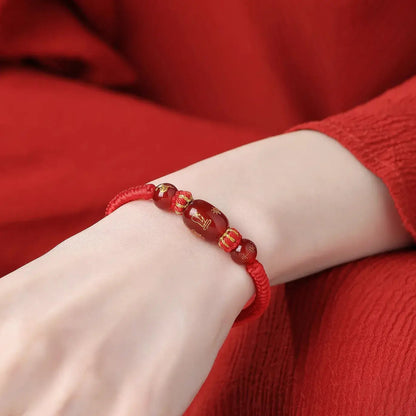 Red beaded bracelet on a wrist against a red background