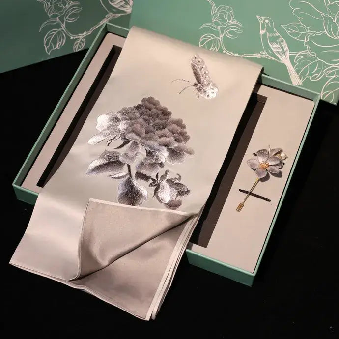 Floral brooch and handkerchief set with matching box on a dark background
