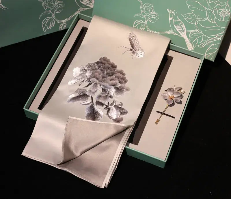 Floral brooch and handkerchief set with matching box on a dark background