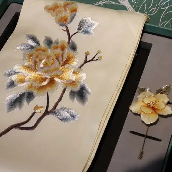 Embroidered flower design on fabric with a matching brooch.