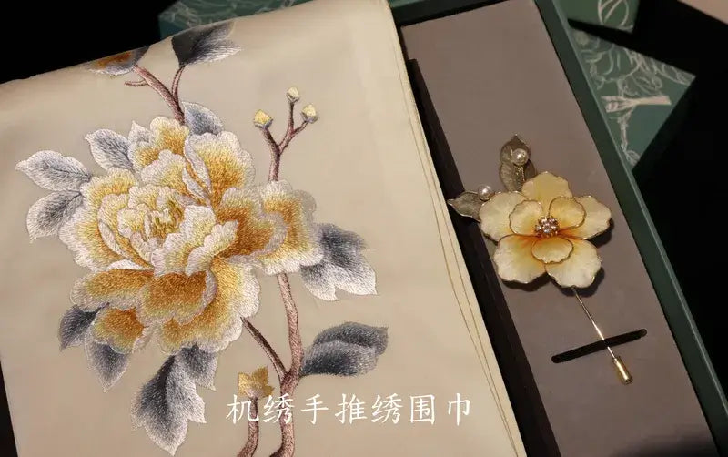 Embroidered flower design on fabric with a matching brooch.