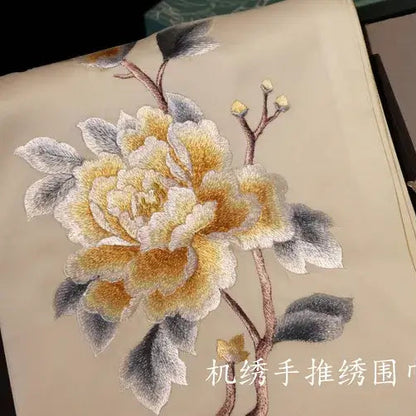 Embroidered flower design on fabric with a matching brooch.