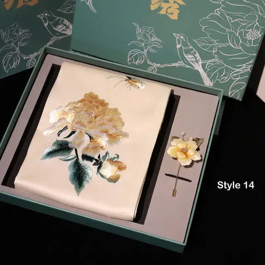 Embroidered floral design on a card with a matching brooch in a decorative box.