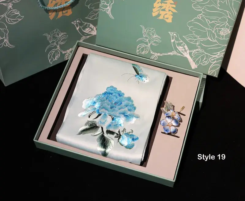 Floral design card and brooch set in a decorative box with floral patterns on the packaging.