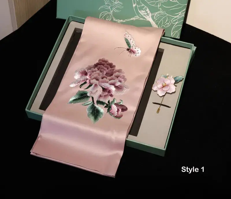 Embroidered pink fabric with floral design and a hairpin in a green box on a black background.