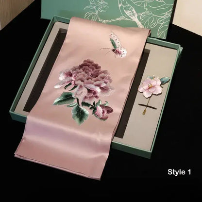 Embroidered pink fabric with floral design and a hairpin in a green box on a black background.