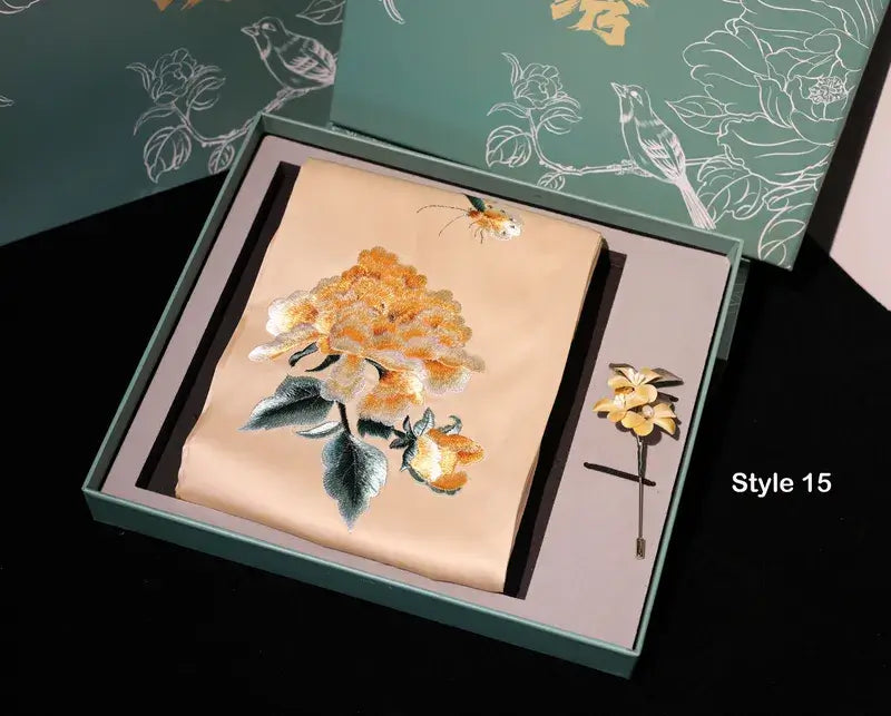 Embroidered floral design on fabric with a matching brooch in a decorative box.