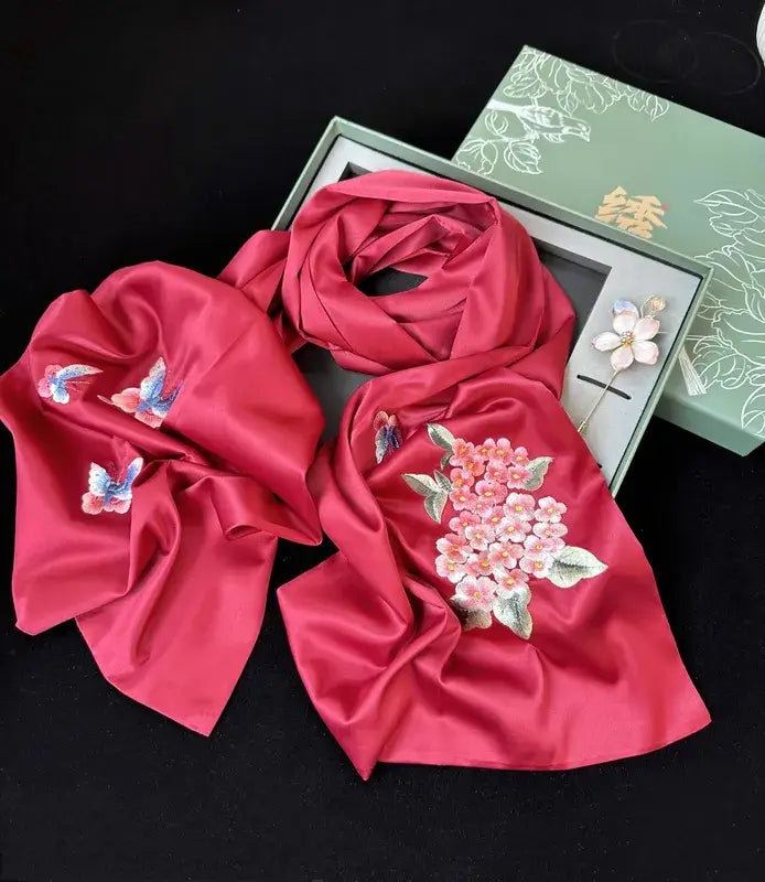 Red scarf with floral and butterfly embroidery on a black background