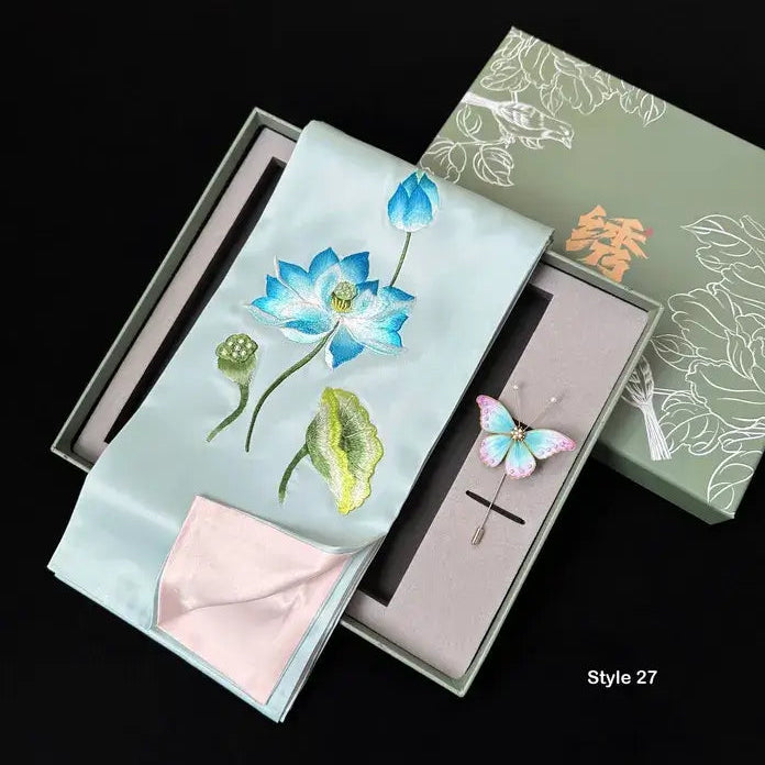 Embroidered fabric with floral design and brooch in a decorative box.