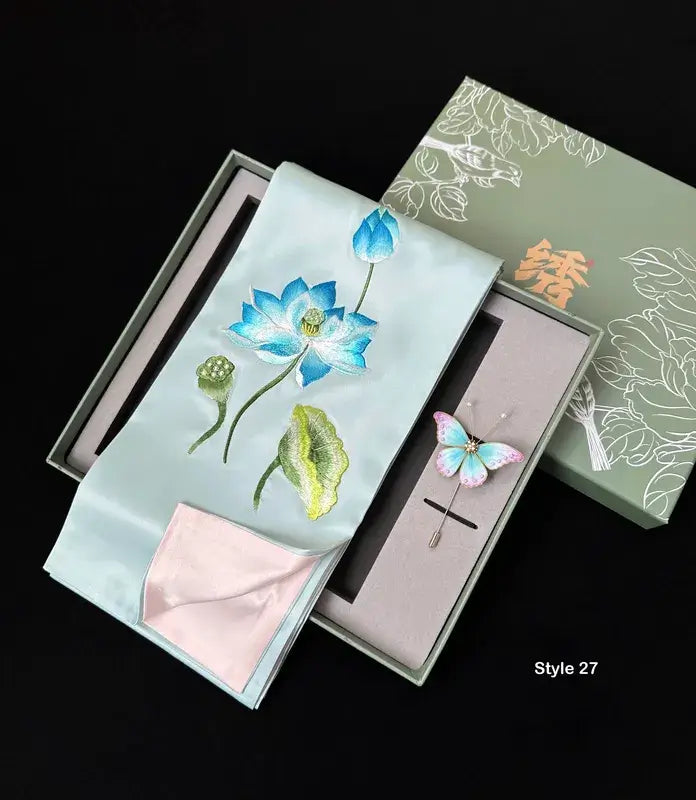 Embroidered fabric with floral design and brooch in a decorative box.