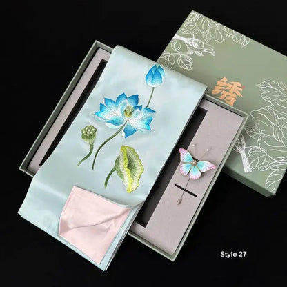 Embroidered fabric with floral design and brooch in a decorative box.