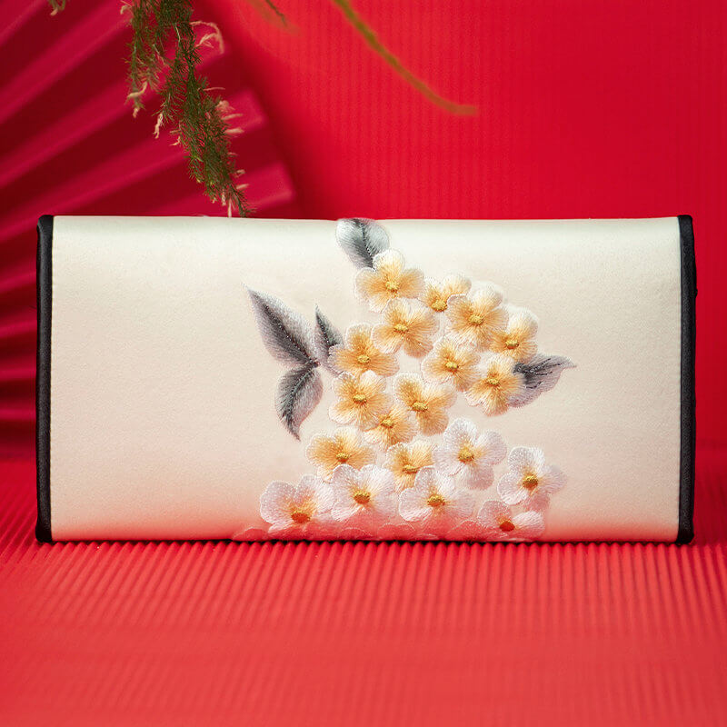 Embroidered clutch bag with floral design on a red background
