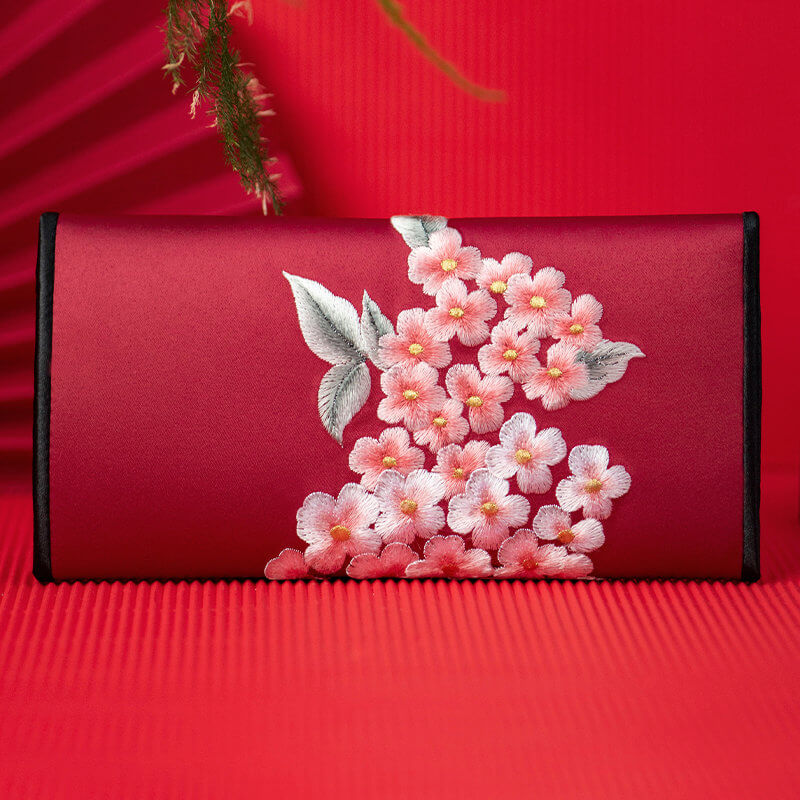 Red pouch with floral embroidery on a red background