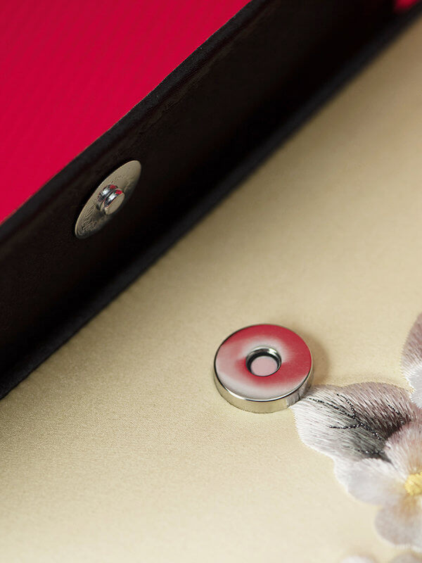 Close-up of a button on a textured surface with a red and black border.