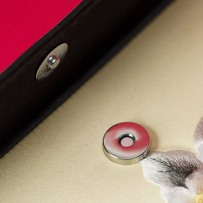 Close-up of a button on a textured surface with a red and black border.