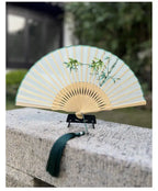 Traditional folding fan with bamboo design on a stone surface