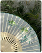 Handheld fan with bamboo design against a natural background