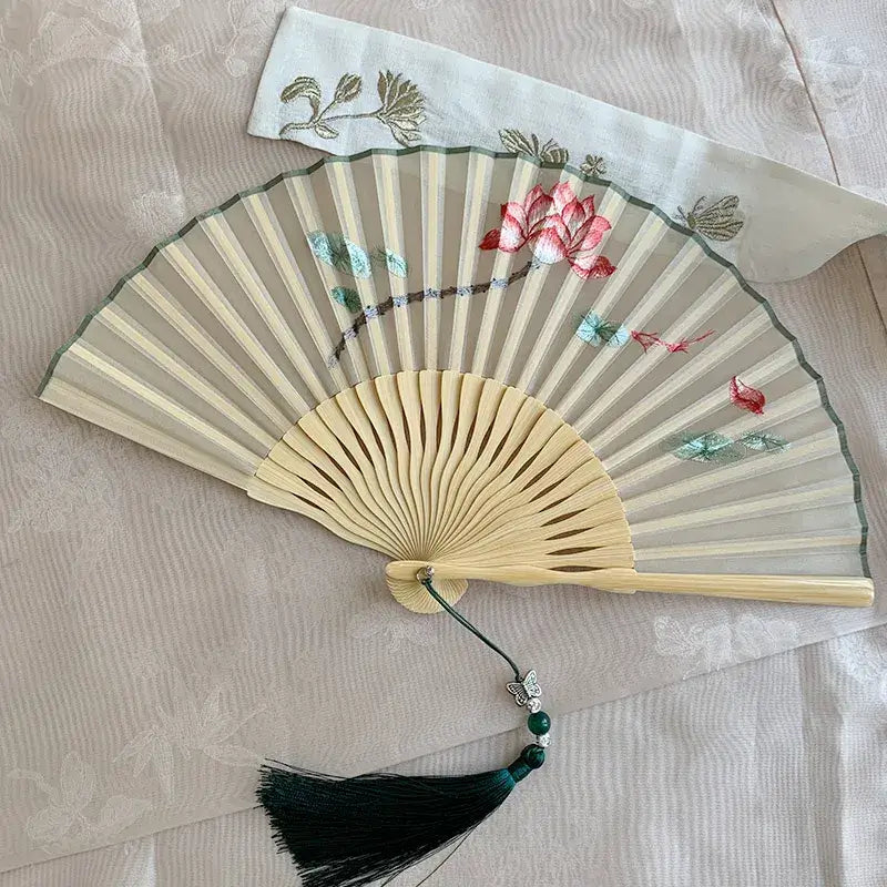 Decorative hand fan with floral designs on a textured surface