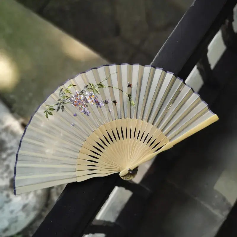 Handheld fan with floral design on a blurred natural background