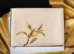 Decorative box with gold floral embroidery on a satin surface