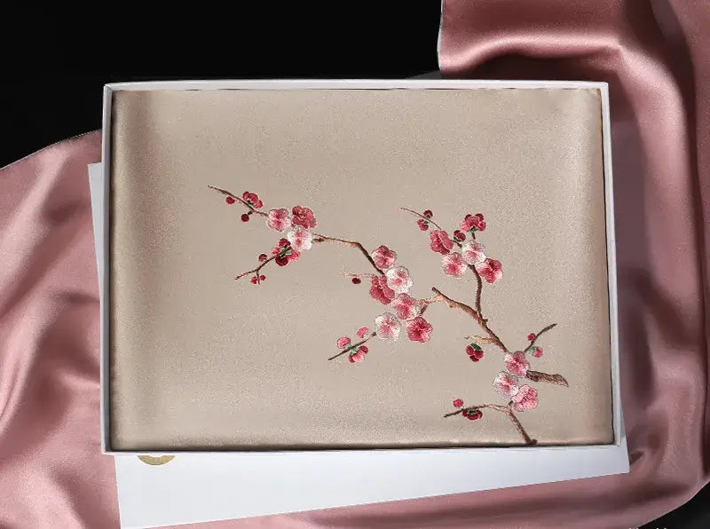 Embroidered box with floral design on a pink fabric background