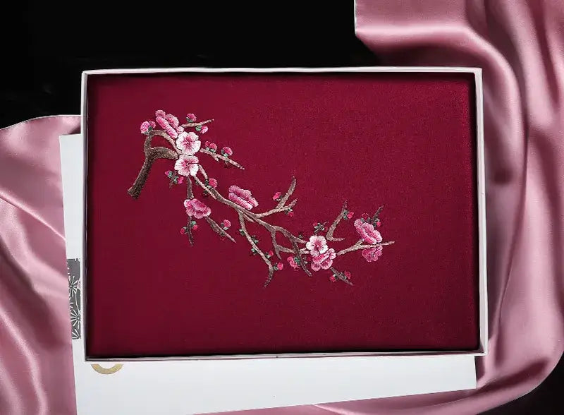 Embroidered box with floral design on a pink fabric background