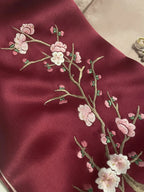 Embroidered cherry blossom design on a red fabric background