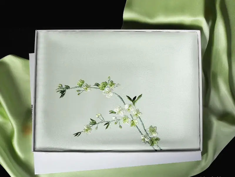 White fabric with embroidered floral design on a green fabric background