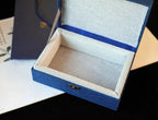 Blue jewelry box with a gold clasp on a dark surface