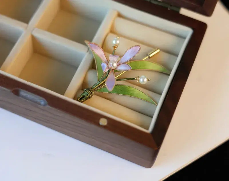 Floral brooch with green leaves and pink flowers in a jewelry box