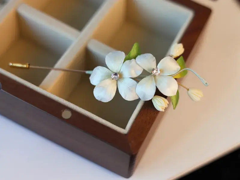 Floral hairpin with green leaves on a wooden box