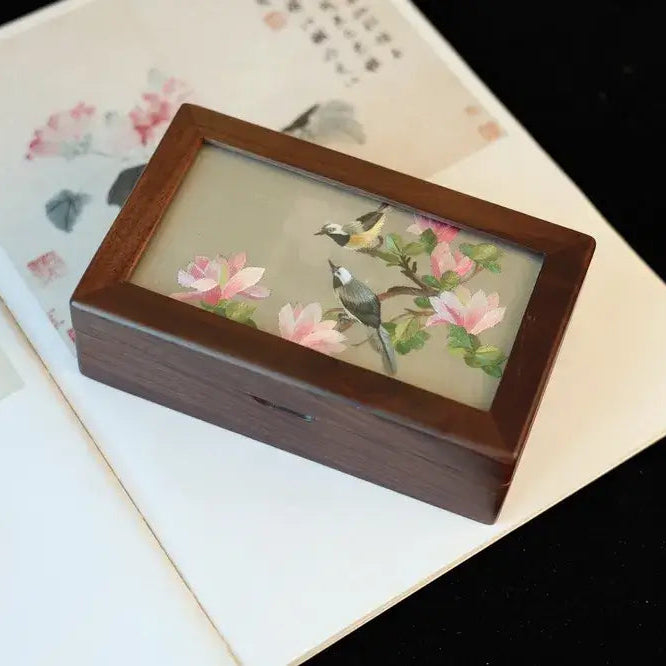 Wooden box with floral and bird design on a textured surface