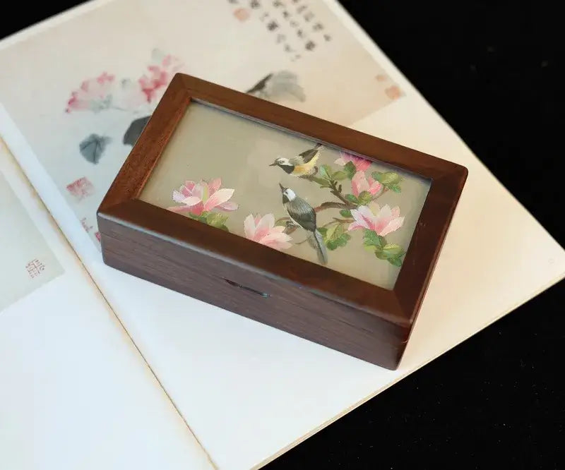 Wooden box with floral and bird design on a textured surface