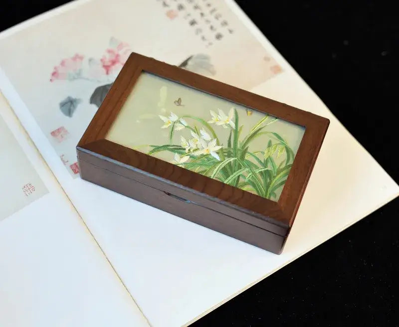 Wooden jewelry box with floral design on a textured surface