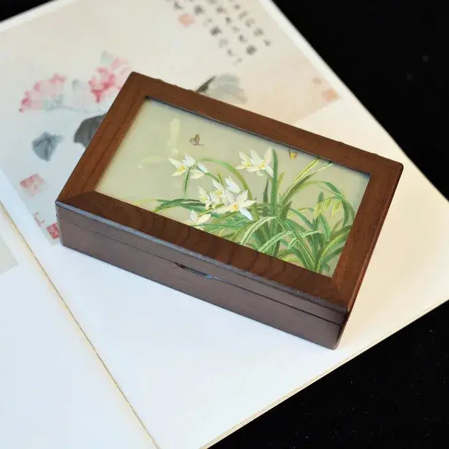 Wooden jewelry box with floral design on a textured surface