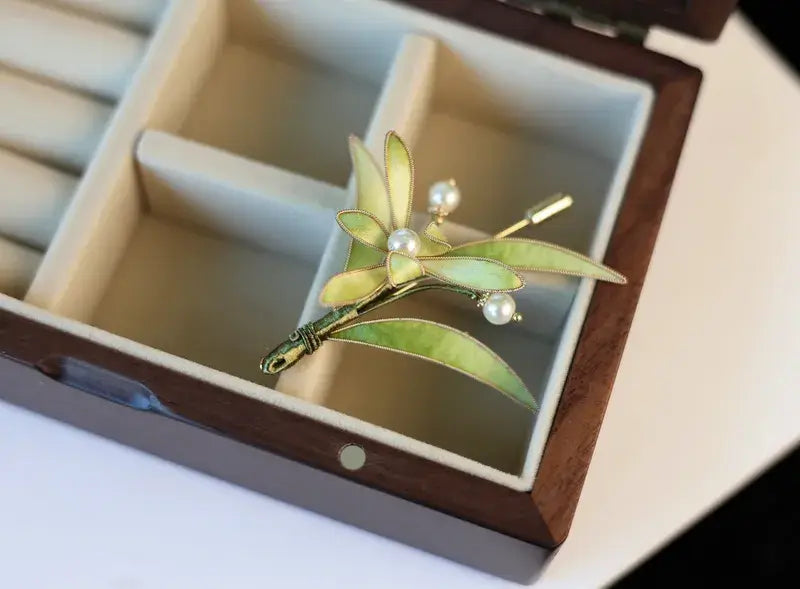 Brooch with green leaves and pearls in a jewelry box