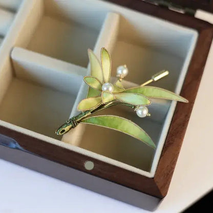 Brooch with green leaves and pearls in a jewelry box