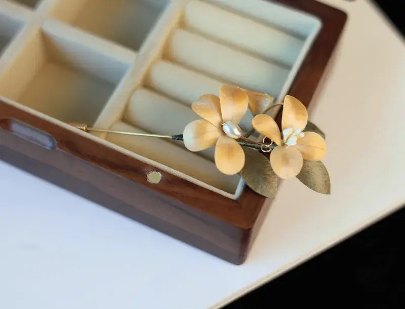 Gold flower-shaped earring in a jewelry box