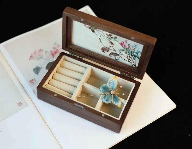 Wooden jewelry box with floral design on lid and interior, containing a butterfly-shaped hairpin.