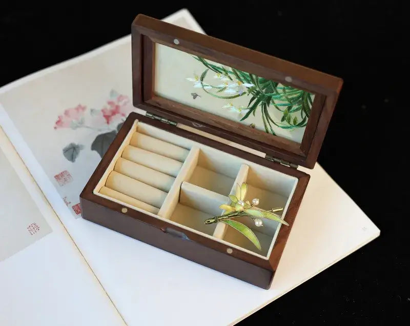 Wooden jewelry box with greenery on a floral-patterned surface