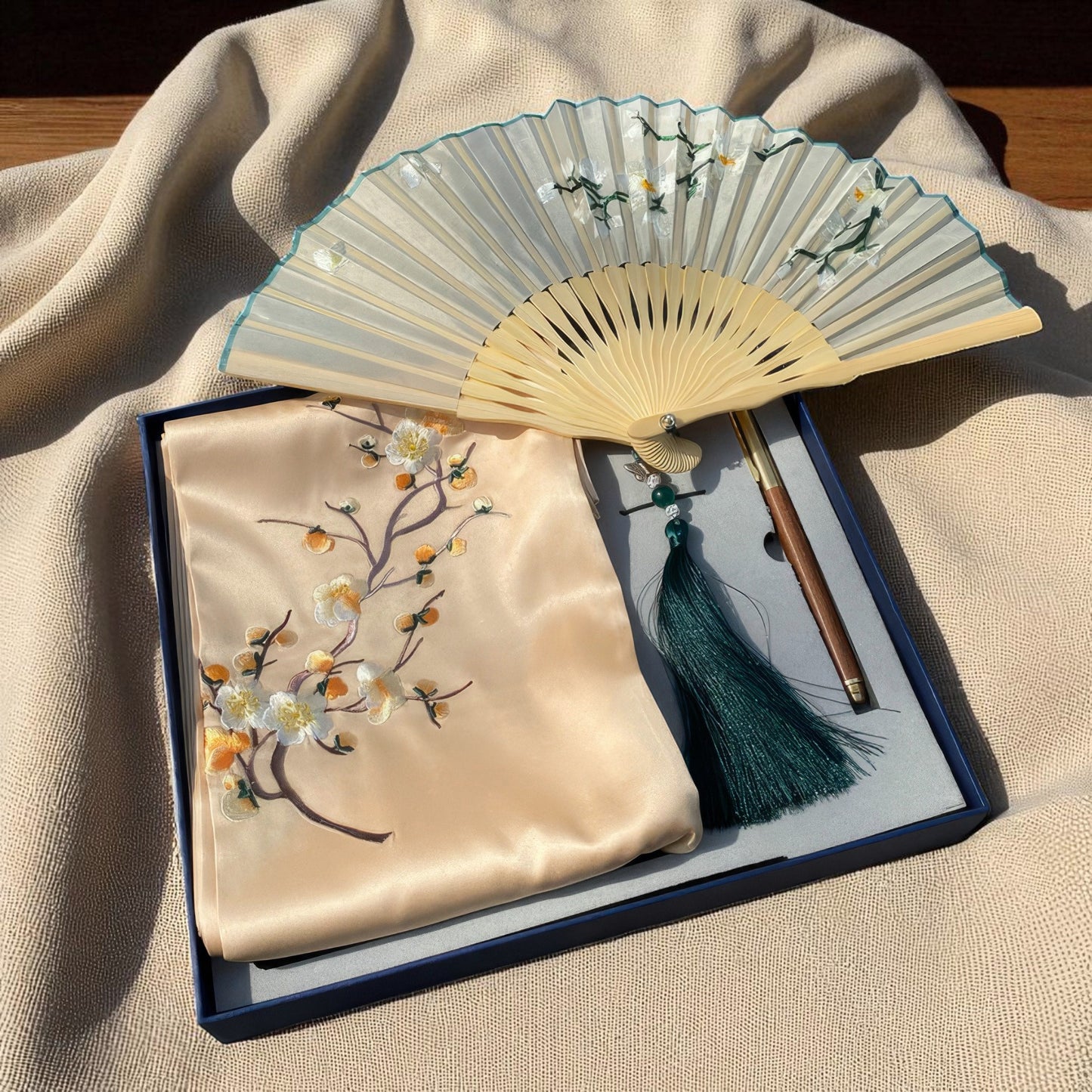 Traditional folding fan with embroidered cover on a beige fabric background