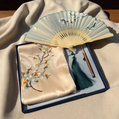 Traditional folding fan with embroidered cover on a beige fabric background