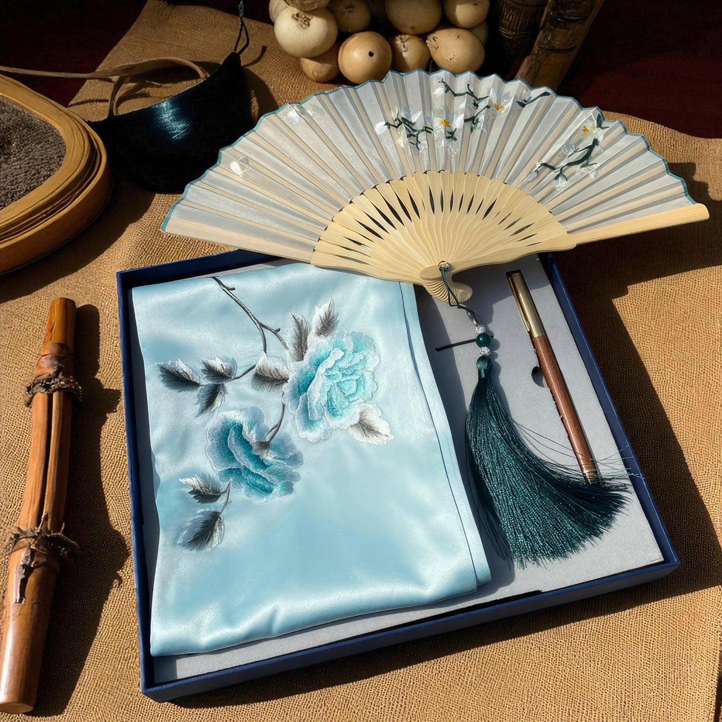 Embroidered notebook with floral design, fan, and brush on a textured surface