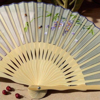 Handheld fan with floral design on gray fabric and wooden handle