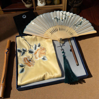 Traditional Japanese fan with embroidered pouch and tassel on a wooden surface