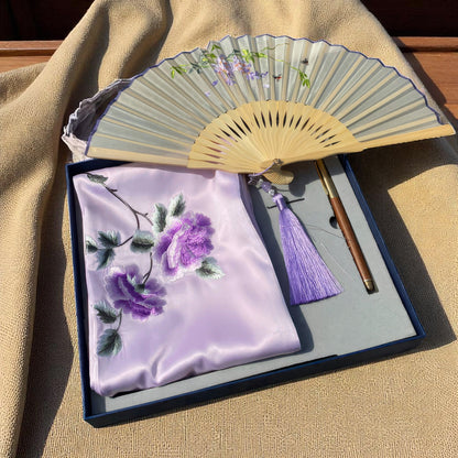 Floral fan and embroidered cloth with tassel on a textured surface