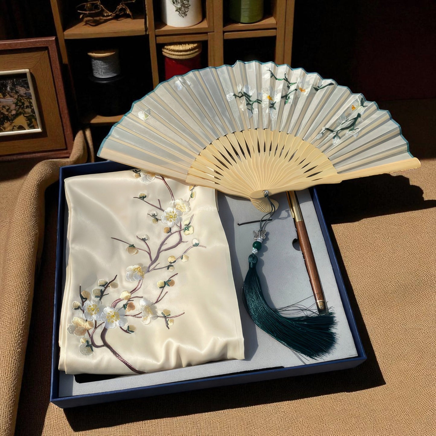 Embroidered fabric with floral design and a folded fan on a box